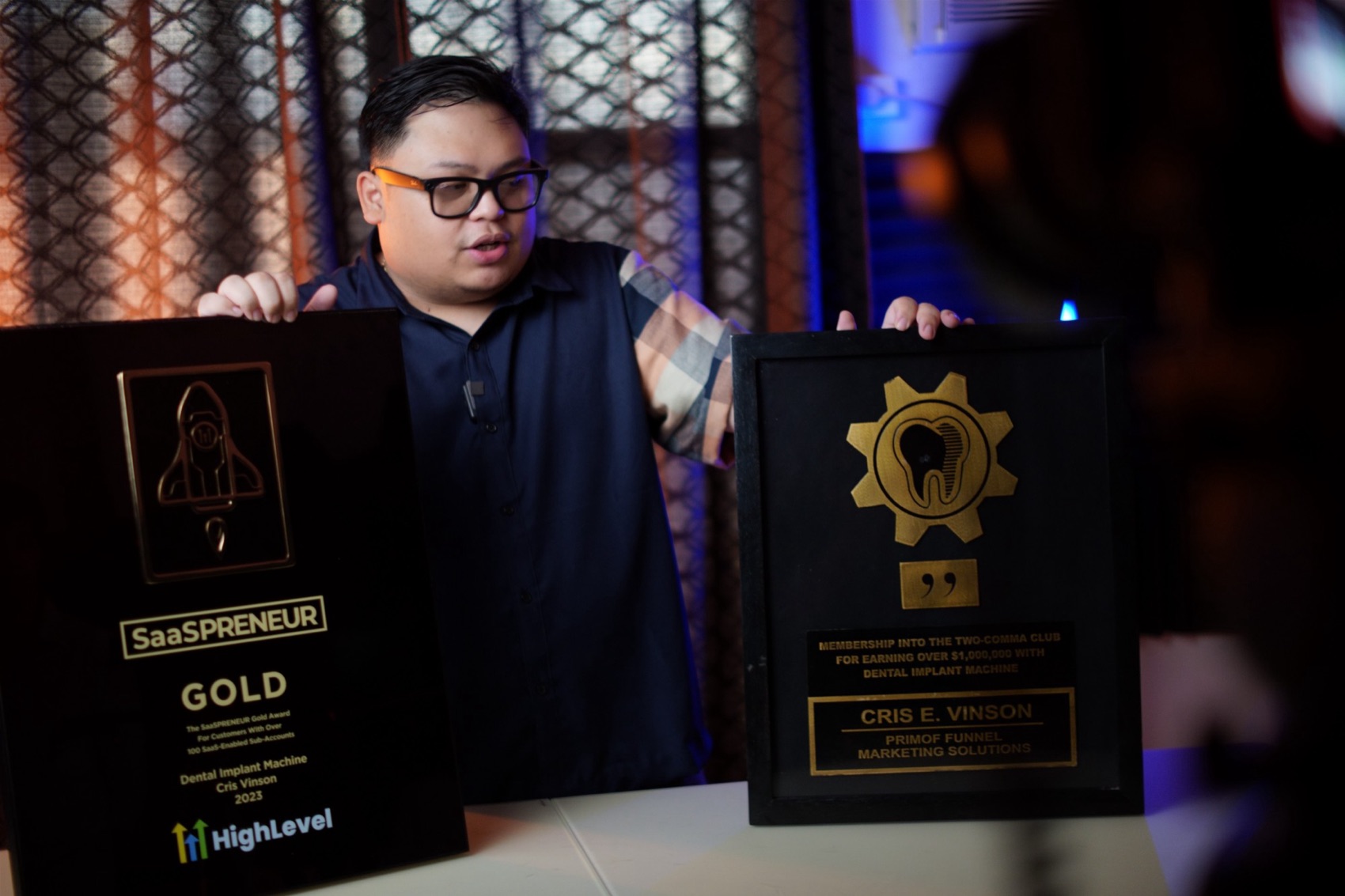 Cris Vinson holding the GoHighLevel SaaSPRENEUR Gold award and Two Comma Club plaque