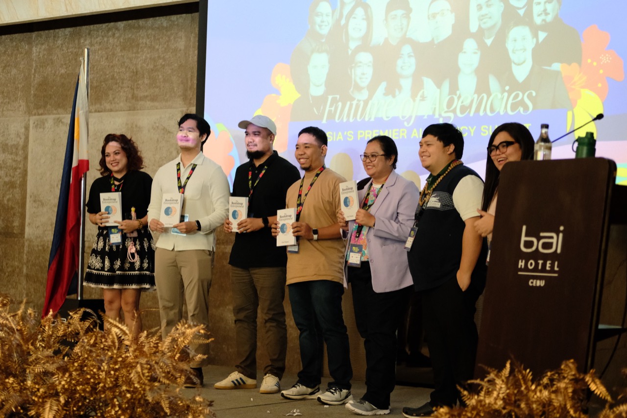 Cris and other attendees holding copies of The Bootstrap Entrepreneur at Cebu Summit